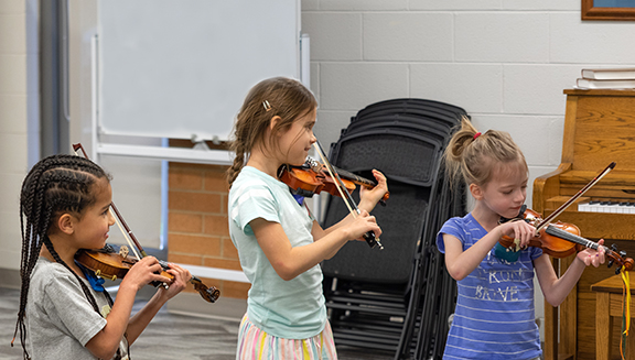 three children playing violins