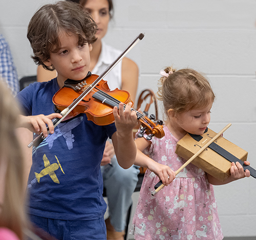 Two children learning violin